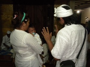 Orang Tua – Ibu Sari menggendong anaknya sementara Ketut Yudi selaku ayah berusaha menghibur “Sang Anak” yang menahan tangisnya pada upacara adat Bali di Tabanan, Senin (29/7/13). 